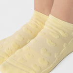 Women wearing a butter yellow full foot grip sock with a raised terry heart pattern made for Pilates, Barre, Yoga, and beyond. 
