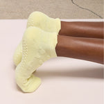 Women on a yoga mat wearing a butter yellow full foot grip sock with a raised terry heart pattern made for Pilates, Barre, Yoga, and beyond. 