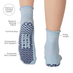 Women wearing a light blue ankle grip sock with a navy blue heart motif on the top made for Pilates, Barre, Yoga, and beyond with product features listed.