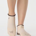 Woman wearing a beige full foot grip sock with a horse on the top and a horseshoe embroidered along the ankle. Made for pilates, barre, and yoga. 