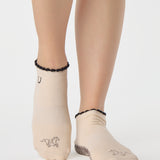 Woman wearing a beige full foot grip sock with a horse on the top and a horseshoe embroidered along the ankle. Made for pilates, barre, and yoga. 