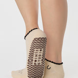Woman wearing a beige full foot grip sock with a horse on the top and a horseshoe embroidered along the ankle. Made for pilates, barre, and yoga. 