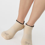 Woman wearing a beige full foot grip sock with a horse on the top and a horseshoe embroidered along the ankle. Made for pilates, barre, and yoga. 