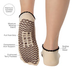 Woman wearing a beige full foot grip sock with a horse on the top and a horseshoe embroidered along the ankle. Made for pilates, barre, and yoga. With the product features listed.