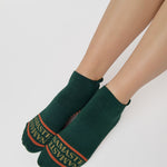 Woman wearing a green full foot grip sock with a yellow namaste message. Made for pilates, barre, yoga, and beyond. 