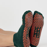 Woman wearing a green full foot grip sock with a yellow namaste message. Made for pilates, barre, yoga, and beyond. 