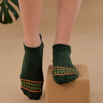 Woman on a yoga block wearing a green full foot grip sock with a yellow namaste message. Made for pilates, barre, yoga, and beyond. 