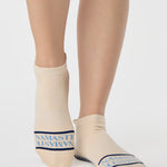 Woman wearing a beige full foot grip sock with a blue namaste message. Made for pilates, barre, yoga, and beyond. 