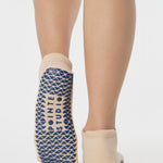 Woman wearing a beige full foot grip sock with a blue namaste message. Made for pilates, barre, yoga, and beyond. 