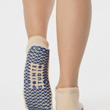 Woman wearing a beige full foot grip sock with a blue namaste message. Made for pilates, barre, yoga, and beyond. 