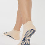Woman wearing a beige full foot grip sock with a blue namaste message. Made for pilates, barre, yoga, and beyond. 