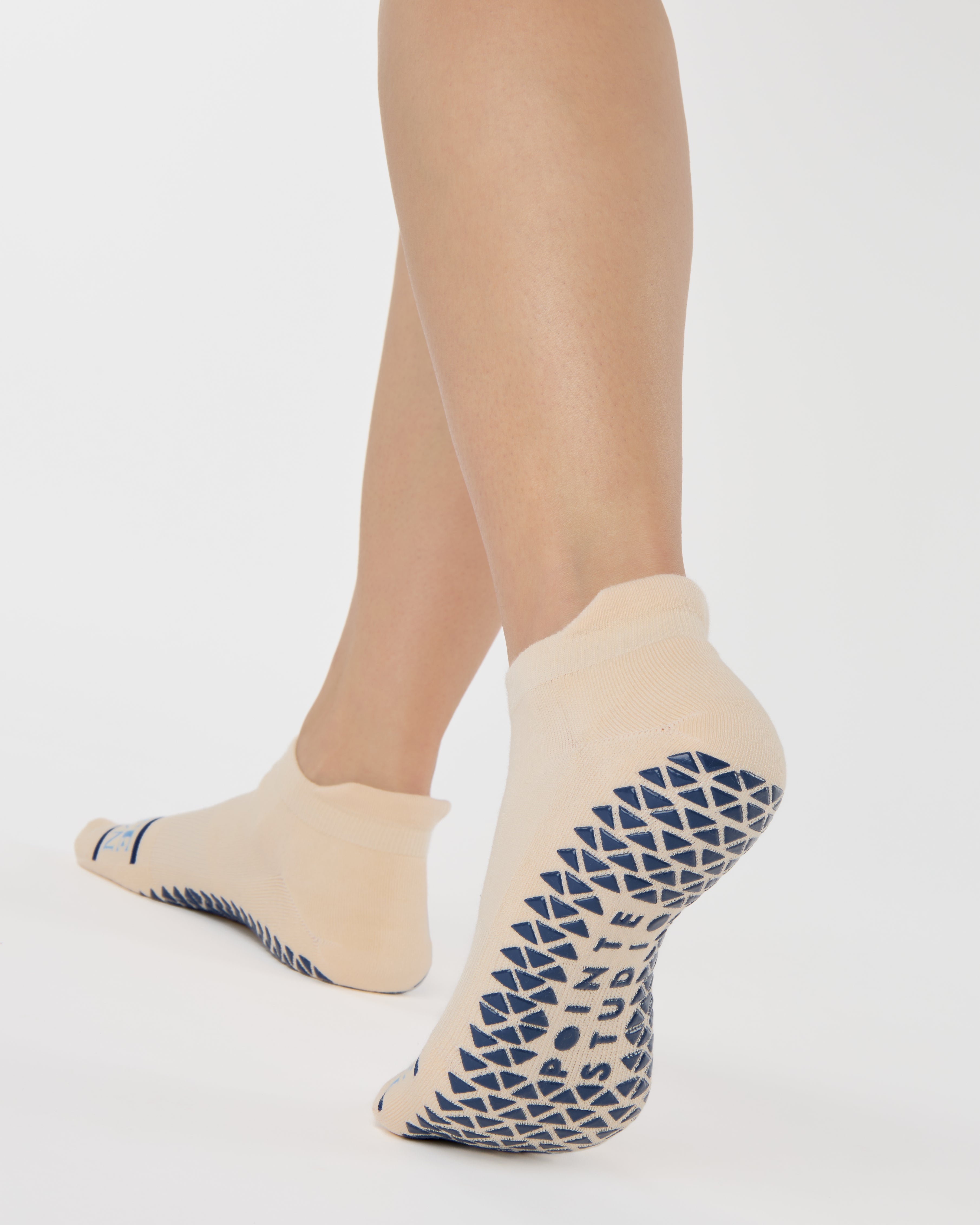 Woman wearing a beige full foot grip sock with a blue namaste message. Made for pilates, barre, yoga, and beyond. 