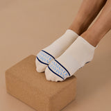 Woman wearing a beige full foot grip sock with a blue namaste message. Made for pilates, barre, yoga, and beyond. 