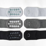 A grip sock pack of mini grip socks for kids ages 4-7, each pair has a happy face motif, black, charcoal and light blue styles.