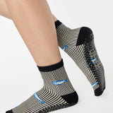 Woman wearing a black and white striped ankle grip sock with sardines swimming around the sock. Made for pilates, barre, yoga, and beyond. 
