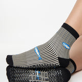 Woman wearing a black and white striped ankle grip sock with sardines swimming around the sock. Made for pilates, barre, yoga, and beyond. 