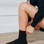 Women wearing a black mid-weight knit grip sock that scrunches, made for Pilates, Barre, Yoga, and Beyond. 