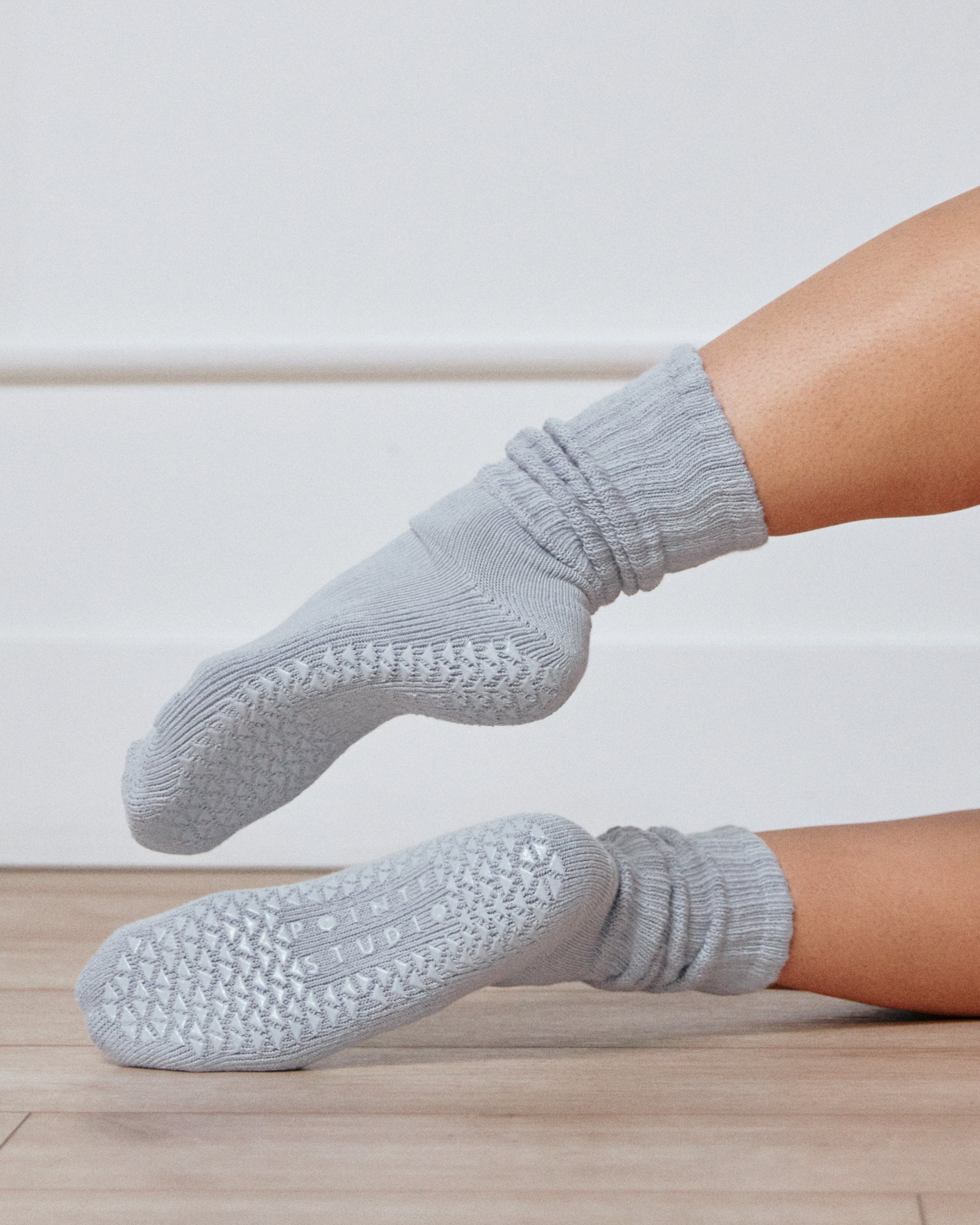 Women wearing a light blue mid-weight knit grip sock that scrunches, made for Pilates, Barre, Yoga, and Beyond. 