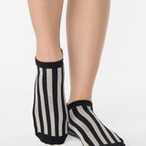 Women wearing a black and grey stripped full foot pilates grip sock, made for pilates, barre, yoga, and beyond.