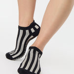 Women wearing a black and grey stripped full foot pilates grip sock, made for pilates, barre, yoga, and beyond.