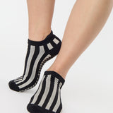 Women wearing a black and grey stripped full foot pilates grip sock, made for pilates, barre, yoga, and beyond.