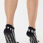 Women wearing a black and grey stripped full foot pilates grip sock, made for pilates, barre, yoga, and beyond.