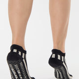 Women wearing a black and grey stripped full foot pilates grip sock, made for pilates, barre, yoga, and beyond.