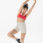 Women wearing a black ankle grip sock with white rows of hearts circling the top ankle made for Pilates, Barre, Yoga, and beyond. 