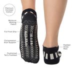 Women wearing a black and grey stripped full foot pilates grip sock, made for pilates, barre, yoga, and beyond. With all the product features listed. 