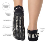 Women wearing a black and grey stripped full foot pilates grip sock, made for pilates, barre, yoga, and beyond. With all the product features listed. 