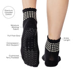 Women wearing a black ankle grip sock with white rows of hearts circling the top ankle made for Pilates, Barre, Yoga, and beyond with product features listed.
