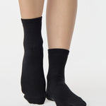 Women wearing a solid black ankle grip sock made for Pilates, Barre, Yoga, and beyond. 