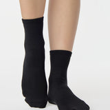 Women wearing a solid black ankle grip sock made for Pilates, Barre, Yoga, and beyond. 