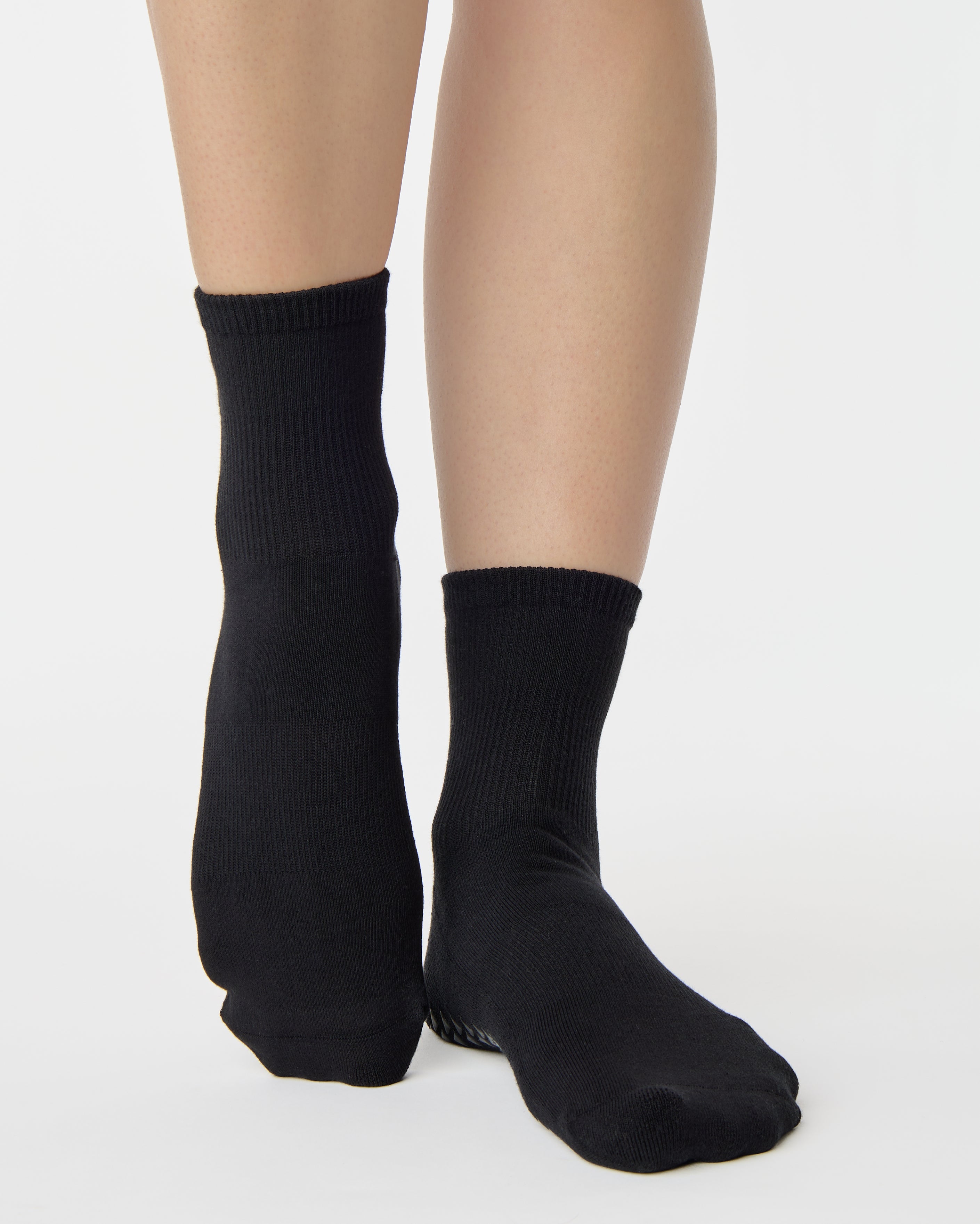 Women wearing a solid black ankle grip sock made for Pilates, Barre, Yoga, and beyond. 