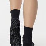 Women wearing a solid black ankle grip sock made for Pilates, Barre, Yoga, and beyond. 