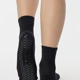 Women wearing a solid black ankle grip sock made for Pilates, Barre, Yoga, and beyond. 