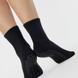 Women wearing a solid black ankle grip sock made for Pilates, Barre, Yoga, and beyond. 