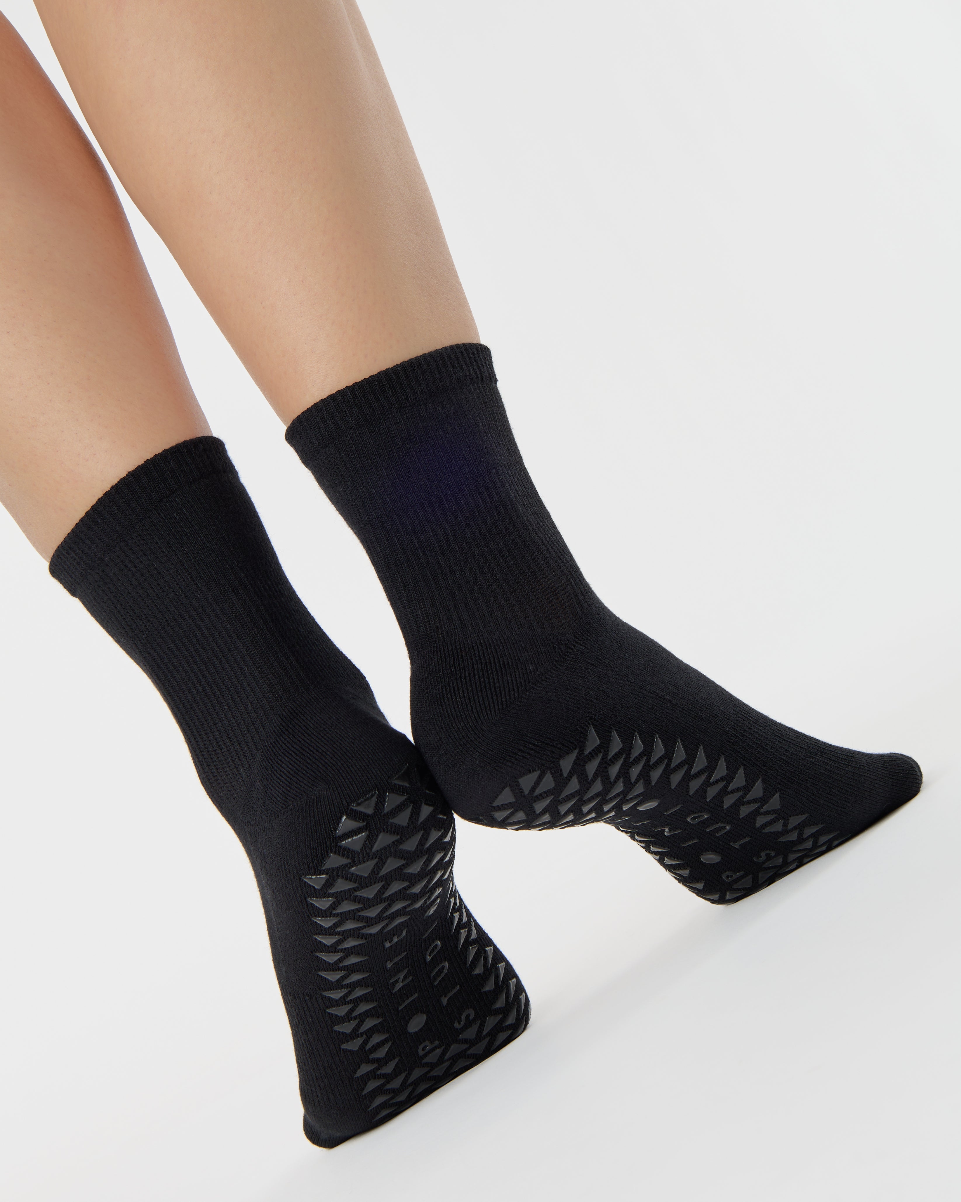 Women wearing a solid black ankle grip sock made for Pilates, Barre, Yoga, and beyond. 