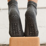 Women wearing a solid charcoal gray ankle grip sock made for Pilates, Barre, Yoga, and beyond. 