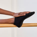 Women wearing a solid black full foot grip sock made for Pilates, Barre, Yoga, and beyond. 