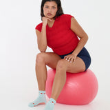 Woman wearing a solid light blue ankle grip sock with red tomatos on garden vines. Made for pilates, yoga, barre, and beyond. 
