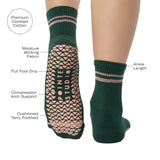 Woman wearing a solid green ankle grip sock with pink stripes on the toes and top ankle cuff made for Pilates, Barre, Yoga, and beyond. With product features listed.