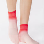 Woman wearing a pink ombre ankle grip sock, made for pilates, barre, yoga, and beyond.