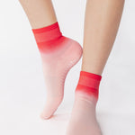 Woman wearing a pink ombre ankle grip sock, made for pilates, barre, yoga, and beyond.