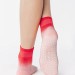 Woman wearing a pink ombre ankle grip sock, made for pilates, barre, yoga, and beyond.