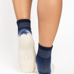 Woman wearing a blue to white ombre ankle grip sock, made for pilates, barre, yoga, and beyond.