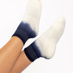 Woman wearing a blue to white ombre ankle grip sock, made for pilates, barre, yoga, and beyond.