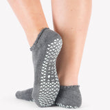Close up photo of a woman's feet wearing grey socks with grip on the bottom of the foot
