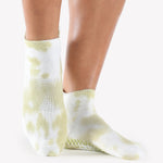 Woman wearing a tie dye light green and white full foot grip sock, made for pilates, barre, yoga, and beyond.