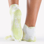 Woman wearing a tie dye light green and white full foot grip sock, made for pilates, barre, yoga, and beyond.